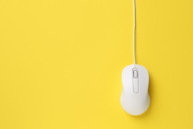 One wired mouse on yellow background, top view. Space for text