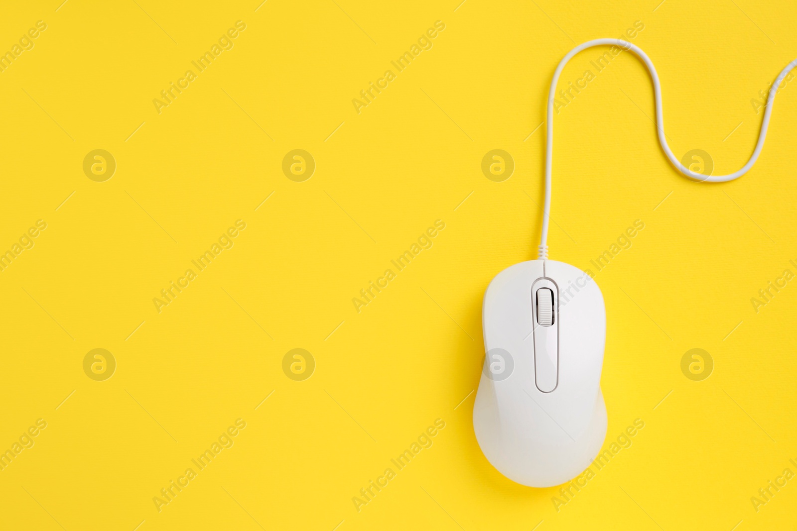 Photo of One wired mouse on yellow background, top view. Space for text