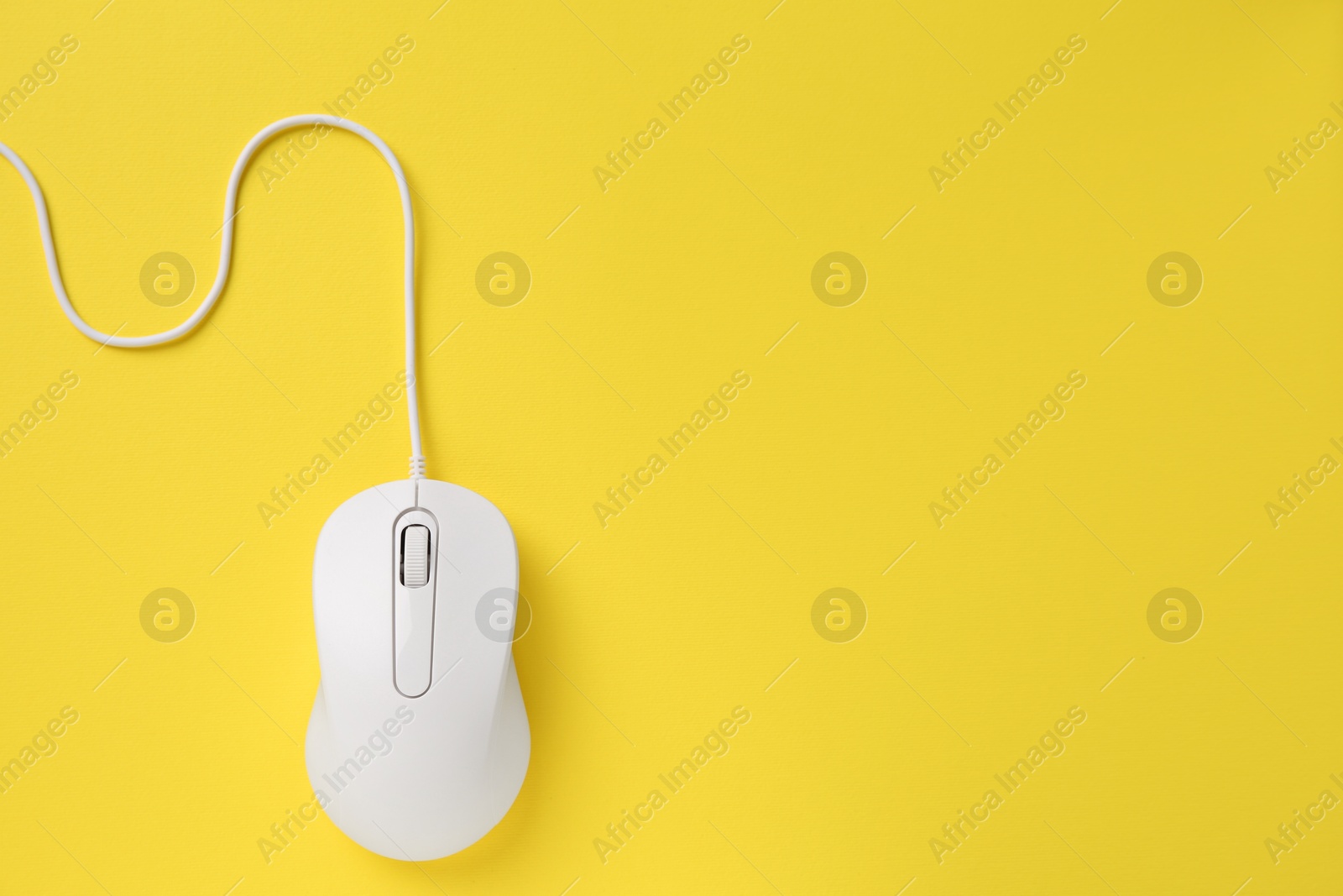 Photo of One wired mouse on yellow background, top view. Space for text