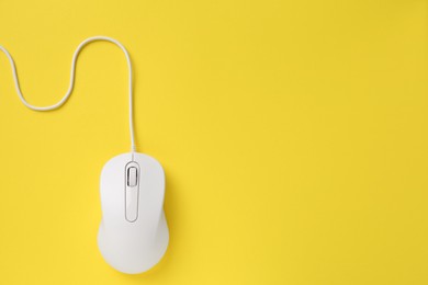 Photo of One wired mouse on yellow background, top view. Space for text