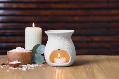 Different aromatherapy products, burning candles and eucalyptus leaves on wooden table, space for text