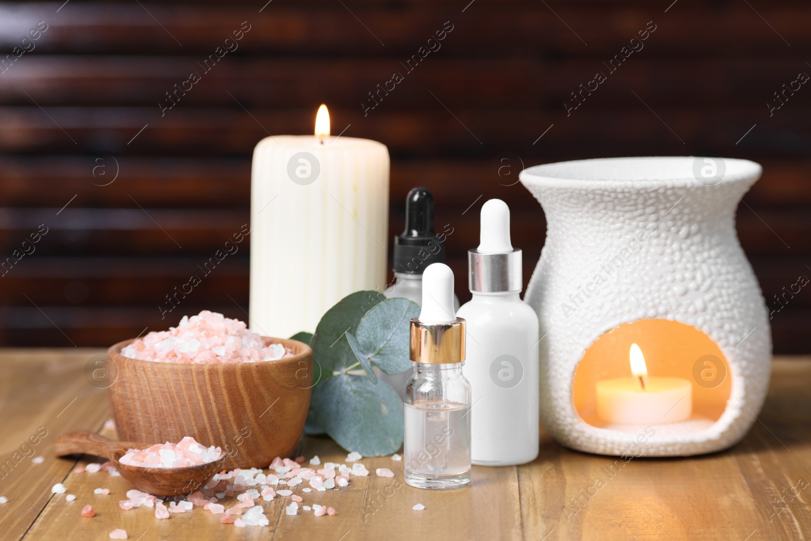 Photo of Different aromatherapy products, burning candles and eucalyptus leaves on wooden table