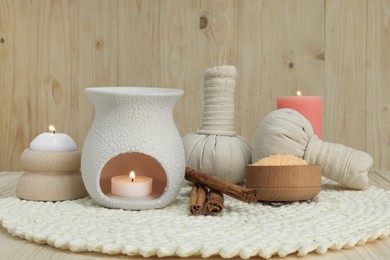Photo of Aromatherapy products and burning candles on wooden table