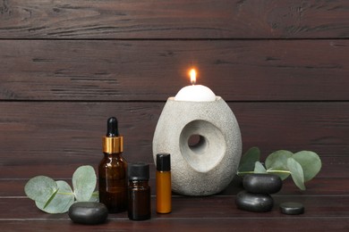 Photo of Aromatherapy products and eucalyptus leaves on wooden table