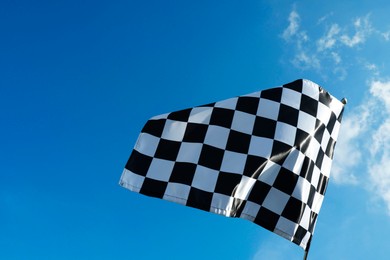 Checkered flag against blue sky outdoors, low angle view. Space for text