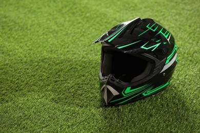 Photo of Modern motorcycle helmet with visor on green grass, space for text