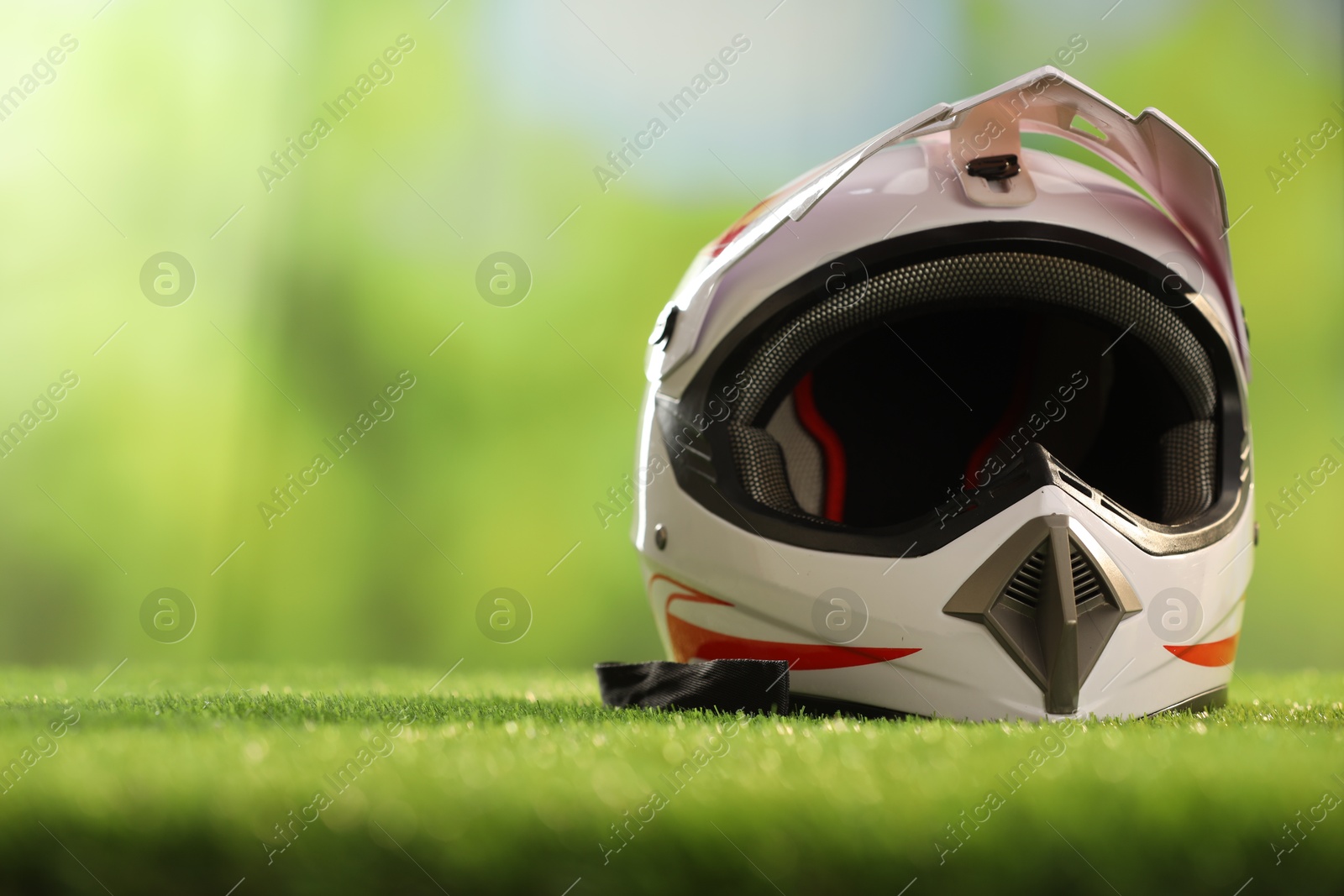 Photo of Modern motorcycle helmet with visor on green grass, space for text