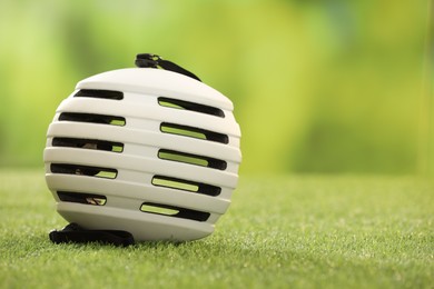 Photo of White protective helmet on green grass, space for text