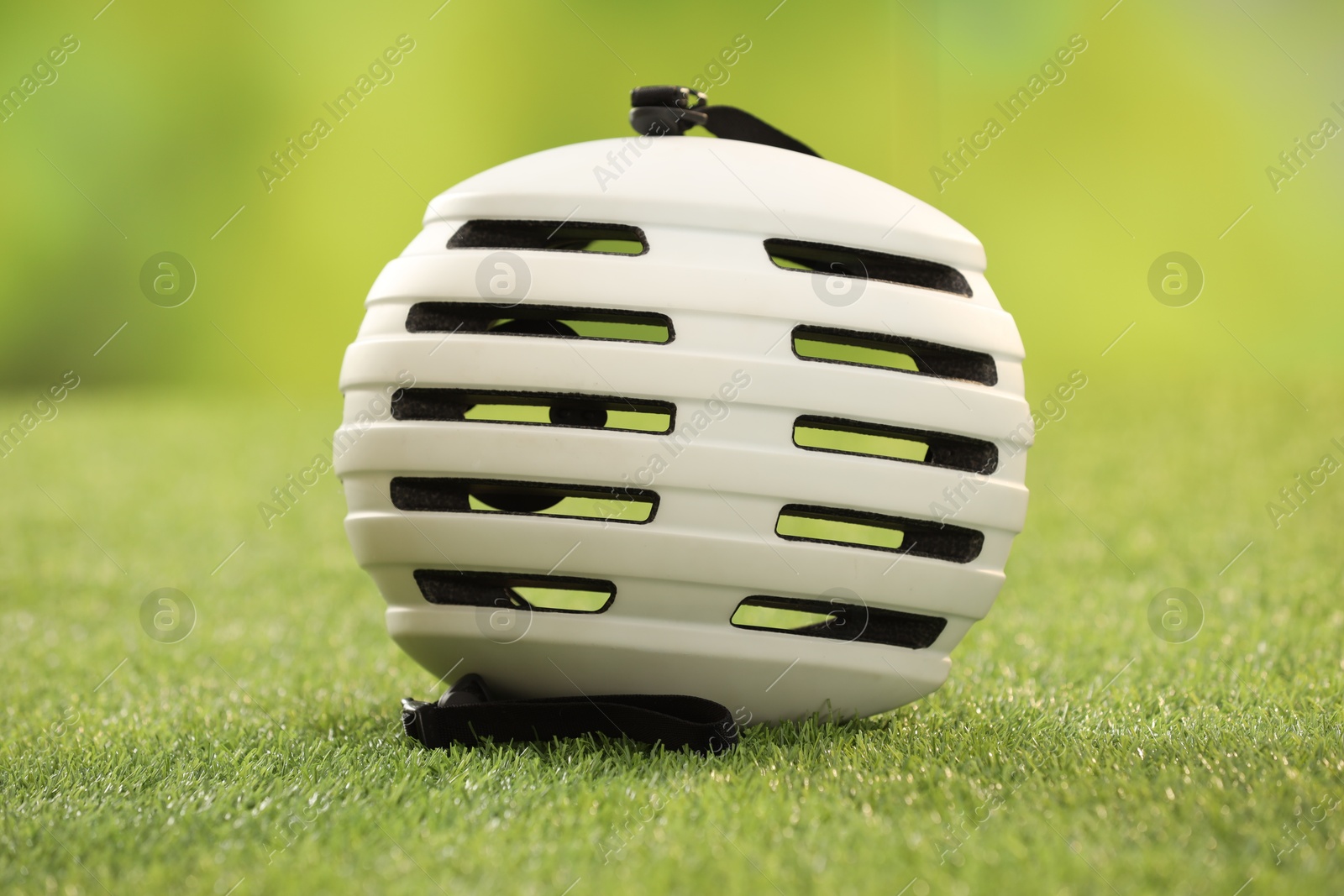 Photo of One white protective helmet on green grass