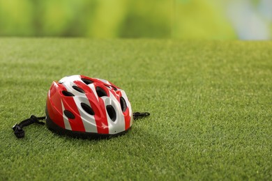 Colorful protective helmet on green grass, space for text