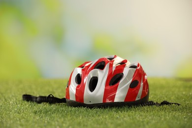 Photo of Colorful protective helmet on green grass, space for text