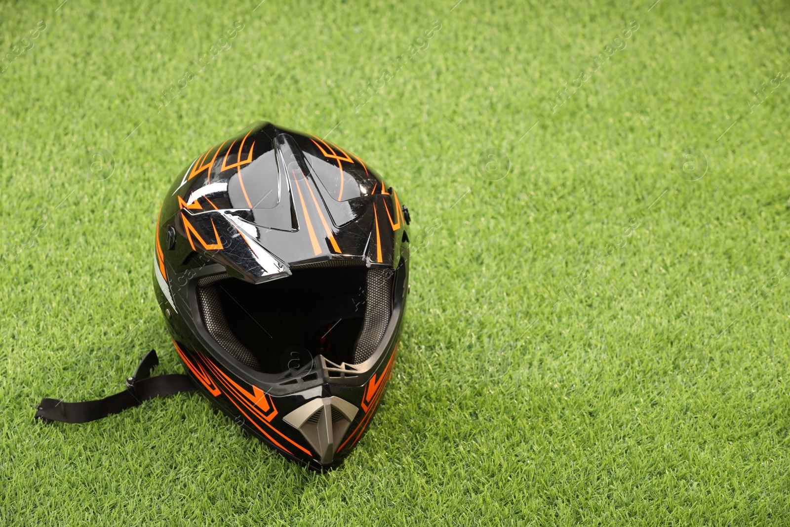 Photo of Modern motorcycle helmet with visor on green grass, space for text