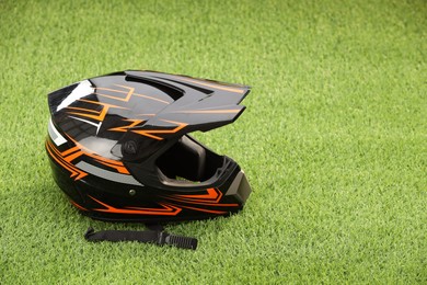 Photo of Modern motorcycle helmet with visor on green grass, space for text