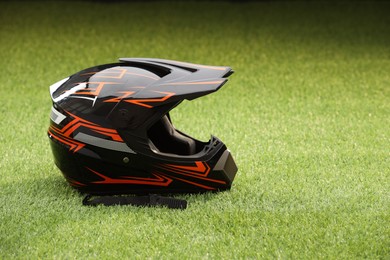 Photo of Modern motorcycle helmet with visor on green grass, space for text