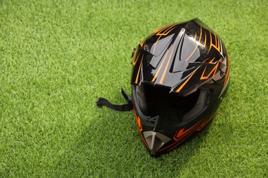 Photo of Modern motorcycle helmet with visor on green grass, space for text