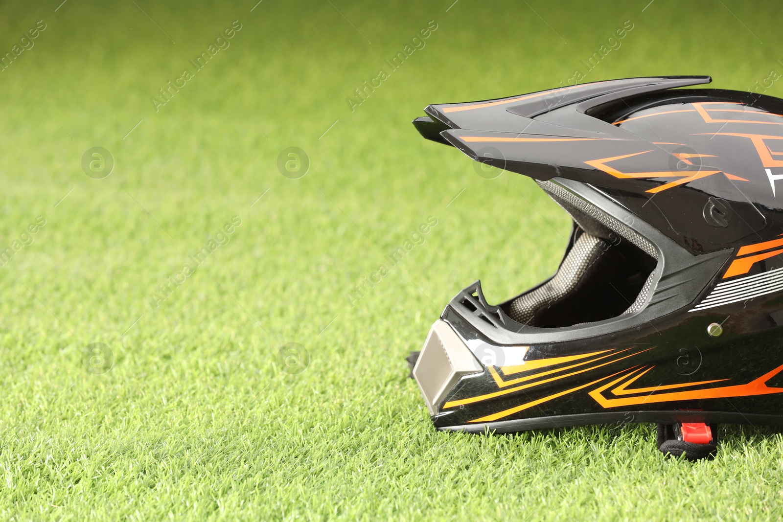 Photo of Modern motorcycle helmet with visor on green grass, space for text