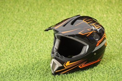 Photo of Modern motorcycle helmet with visor on green grass, space for text