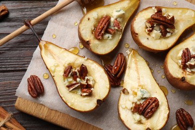 Photo of Tasty baked pears with nuts, blue cheese, thyme and honey on wooden table, top view