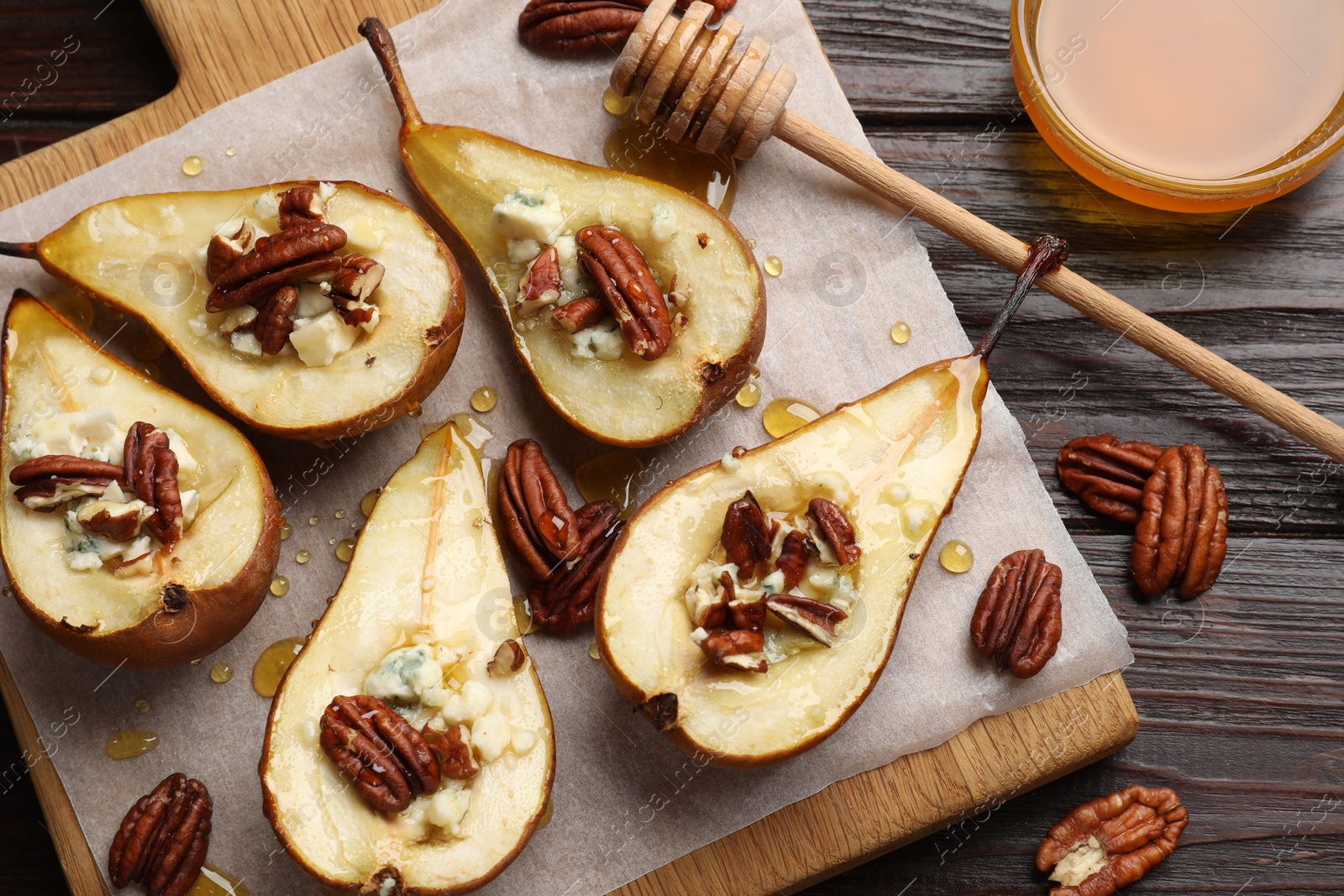 Photo of Tasty baked pears with nuts, blue cheese, thyme and honey on wooden table, flat lay