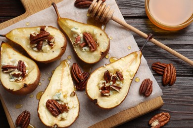 Tasty baked pears with nuts, blue cheese, thyme and honey on wooden table, flat lay