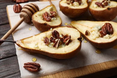 Tasty baked pears with nuts, blue cheese, thyme and honey on wooden table, closeup