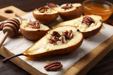 Tasty baked pears with nuts, blue cheese, thyme and honey on wooden table, closeup