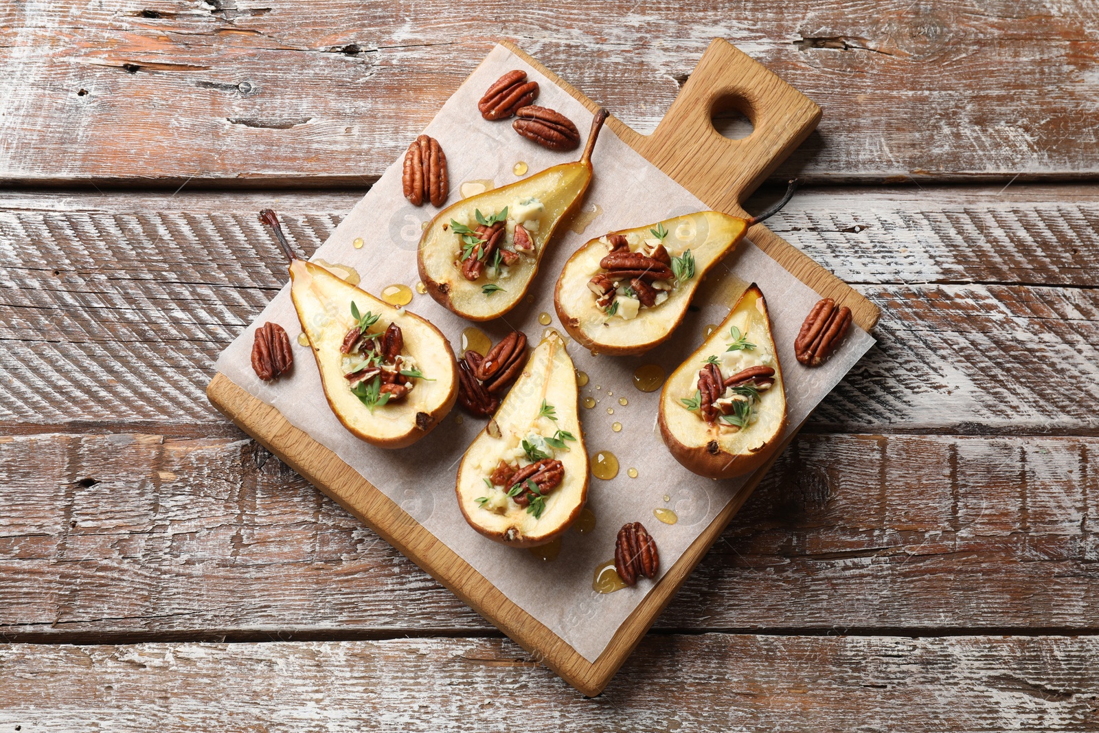 Photo of Tasty baked pears with nuts, blue cheese, thyme and honey on wooden table, top view