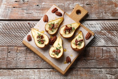 Photo of Tasty baked pears with nuts, blue cheese, thyme and honey on wooden table, top view