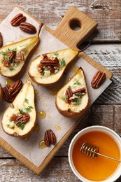 Photo of Tasty baked pears with nuts, blue cheese, thyme and honey on wooden table, top view