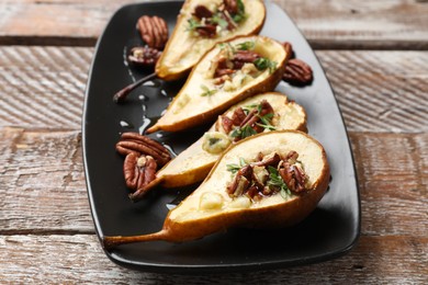 Photo of Tasty baked pears with nuts, blue cheese, thyme and honey on wooden table