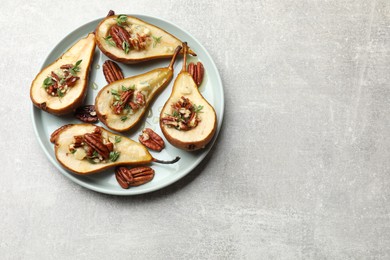 Tasty baked pears with nuts, blue cheese, thyme and honey on light grey table, top view. Space for text