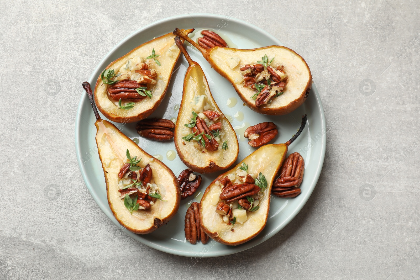 Photo of Tasty baked pears with nuts, blue cheese, thyme and honey on light grey table, top view