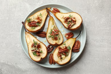 Tasty baked pears with nuts, blue cheese, thyme and honey on light grey table, top view