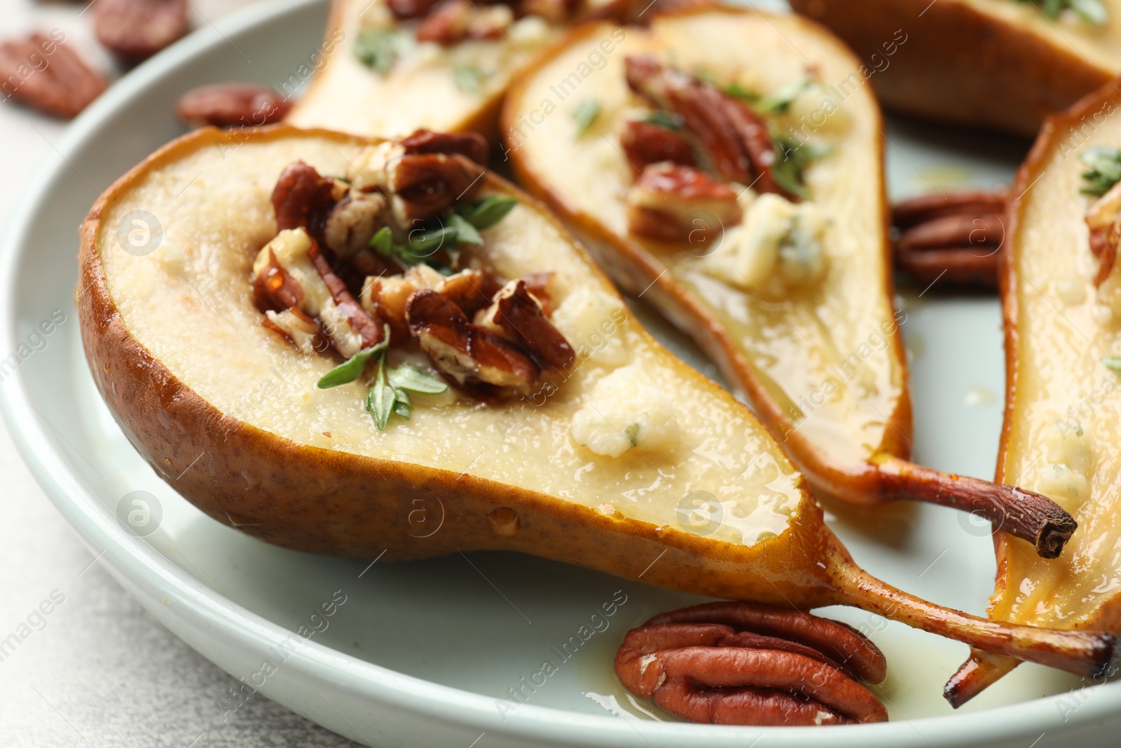 Photo of Tasty baked pears with nuts, blue cheese, thyme and honey on table, closeup