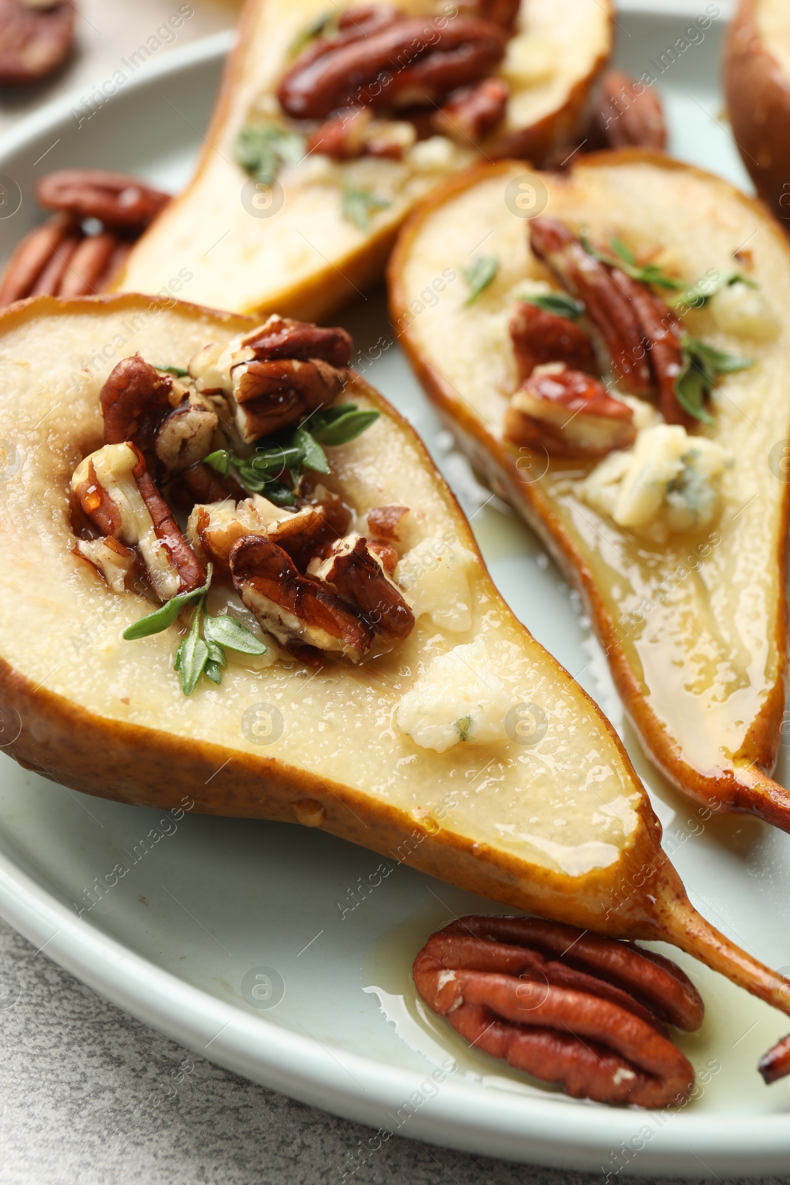 Photo of Tasty baked pears with nuts, blue cheese, thyme and honey on table, closeup