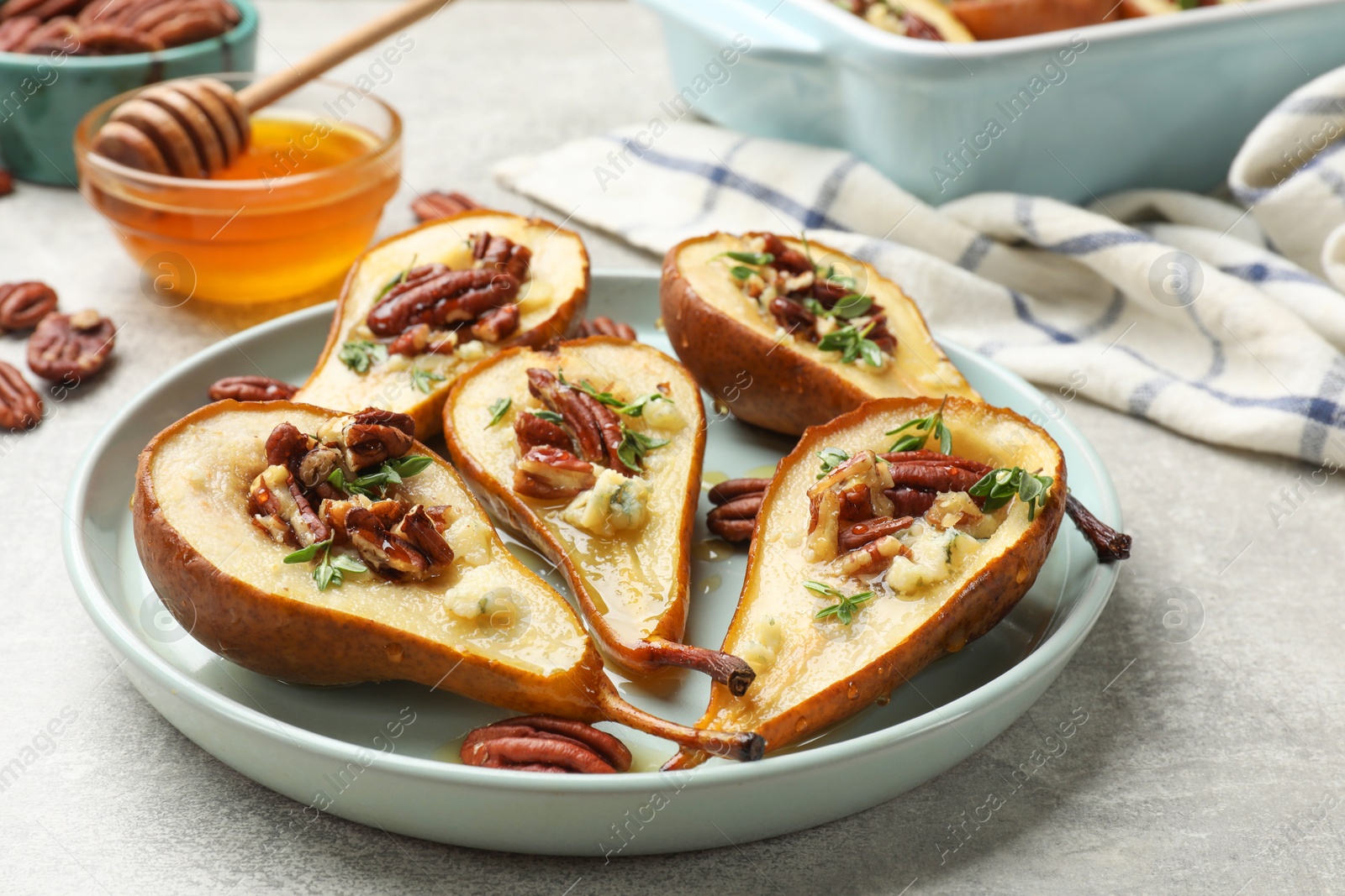 Photo of Tasty baked pears with nuts, blue cheese, thyme and honey on light grey table