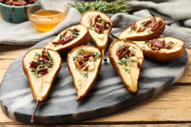 Tasty baked pears with nuts, blue cheese, thyme and honey on wooden table