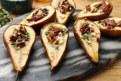 Tasty baked pears with nuts, blue cheese, thyme and honey on wooden table