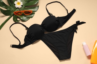 Photo of Flat lay composition with black swimsuit, sunscreens and sunglasses on beige background