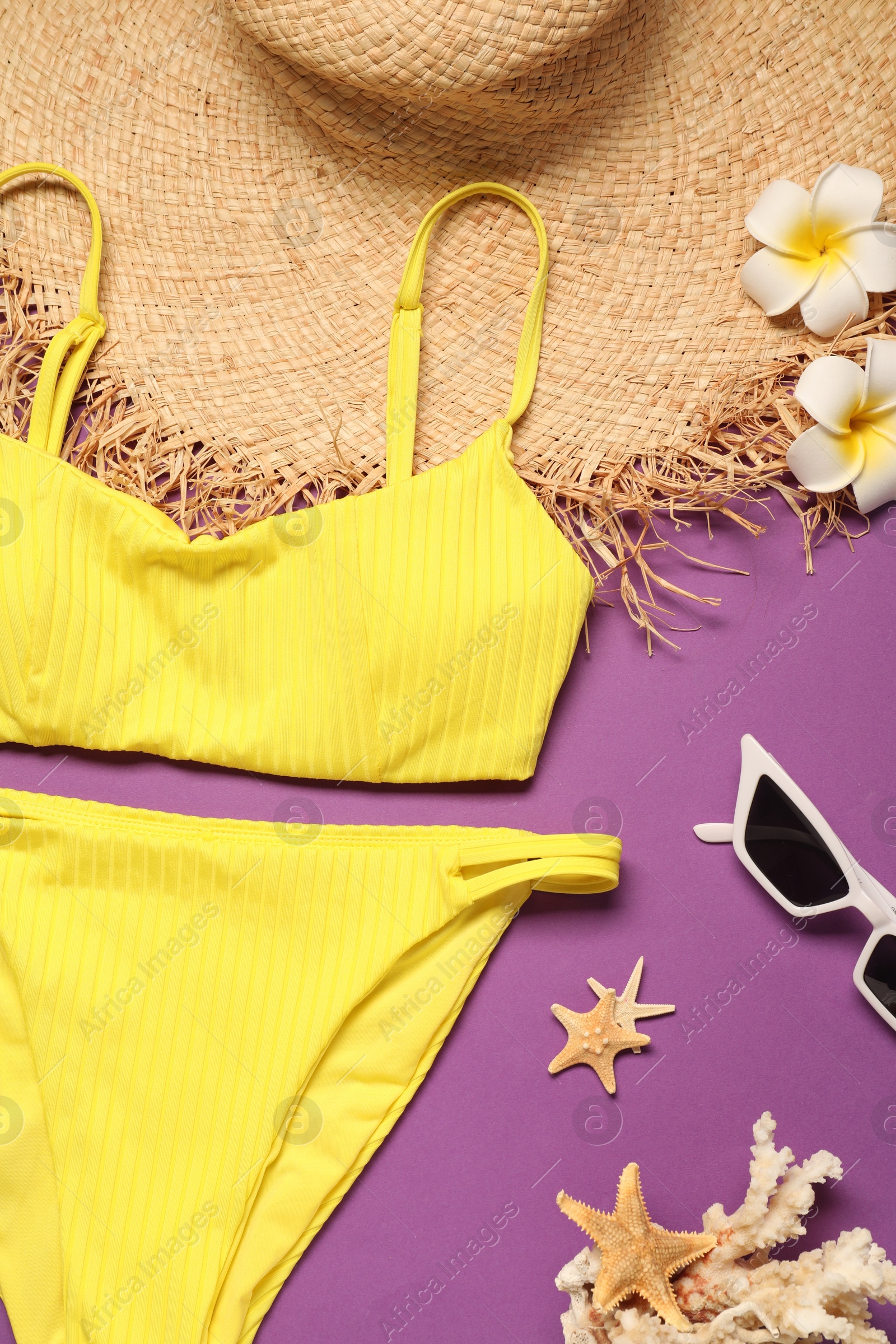 Photo of Flat lay composition with yellow swimsuit, hat and sunglasses on purple background