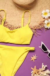 Flat lay composition with yellow swimsuit, hat and sunglasses on purple background