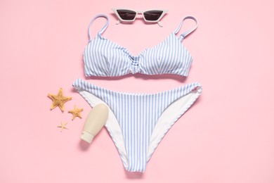 Photo of Striped swimsuit, sunscreen, sunglasses and starfishes on pink background, flat lay