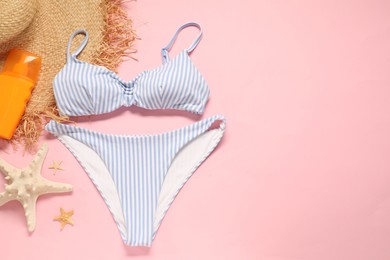 Photo of Striped swimsuit, sunscreen, hat and starfishes on pink background, flat lay. Space for text