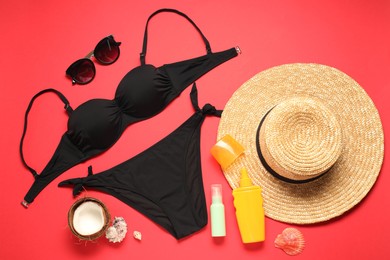 Photo of Flat lay composition with black swimsuit, hat and sunglasses on red background