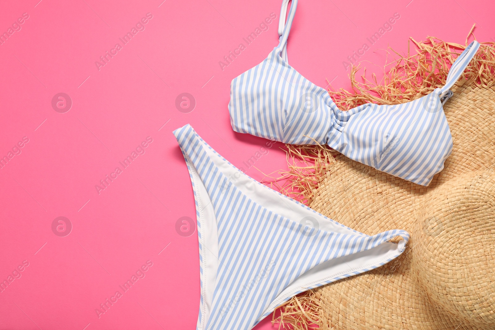 Photo of Striped swimsuit and hat on pink background, flat lay. Space for text