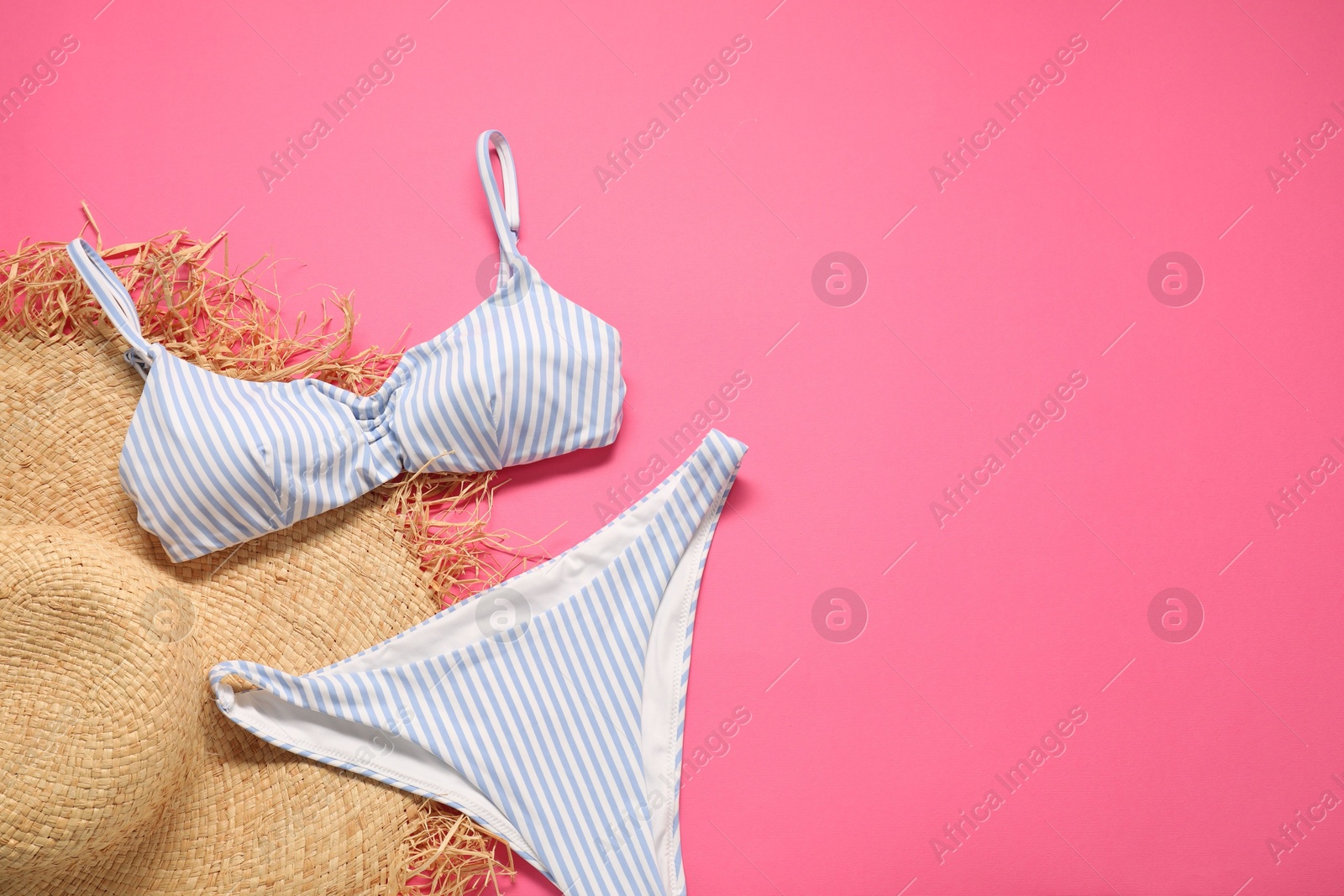 Photo of Striped swimsuit and hat on pink background, flat lay. Space for text