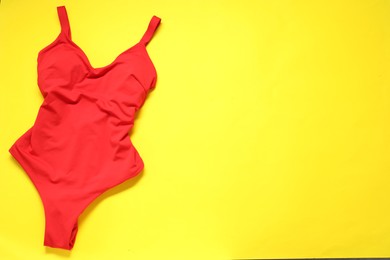 Red swimsuit on yellow background, top view. Space for text