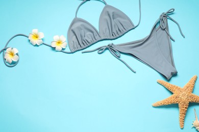 Photo of Flat lay composition with beautiful swimsuit, flowers and starfish on light blue background. Space for text