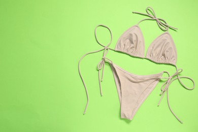Photo of Beige swimsuit on green background, top view. Space for text
