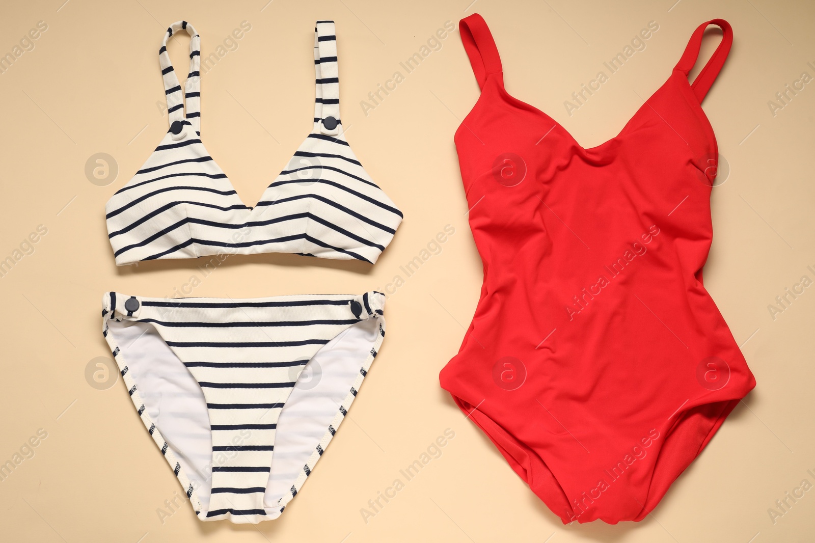 Photo of Two beautiful swimsuits on beige background, flat lay